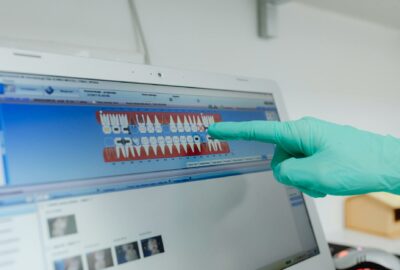 Dentist demonstrates dental software on monitor pointing with gloved hand